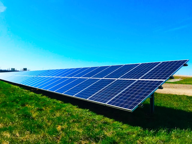 Solar panels in large field with blue sky in the background.