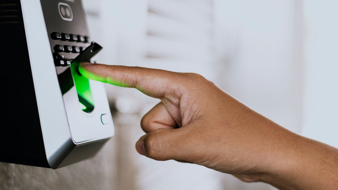 Fingerprint scan on a biometric access control keypad, illuminated green.