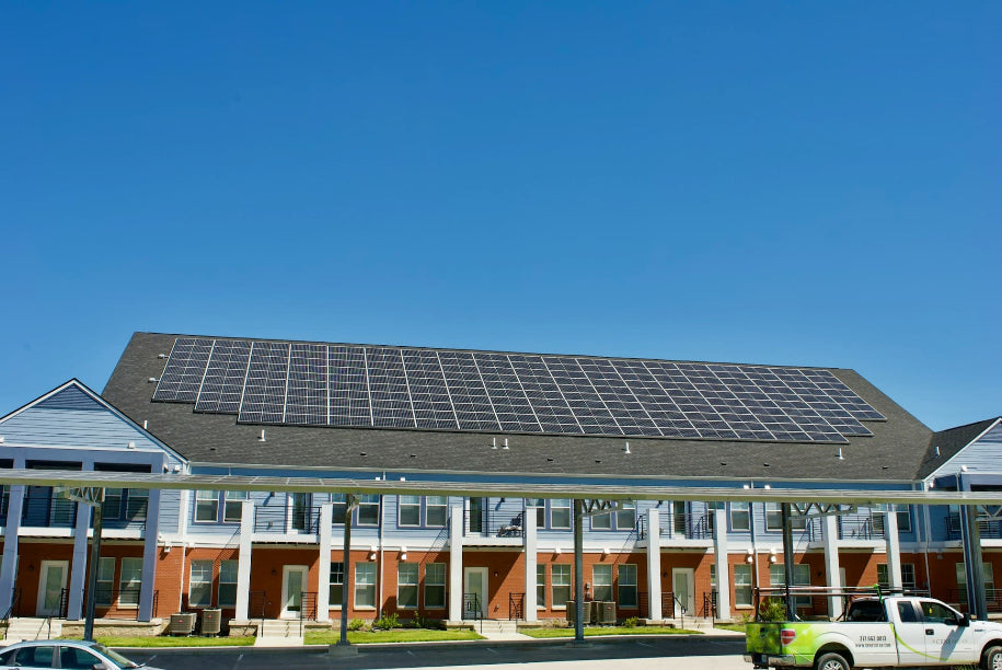 Large solar panel array on the roof of a commercial building with covered walkways and parking below.