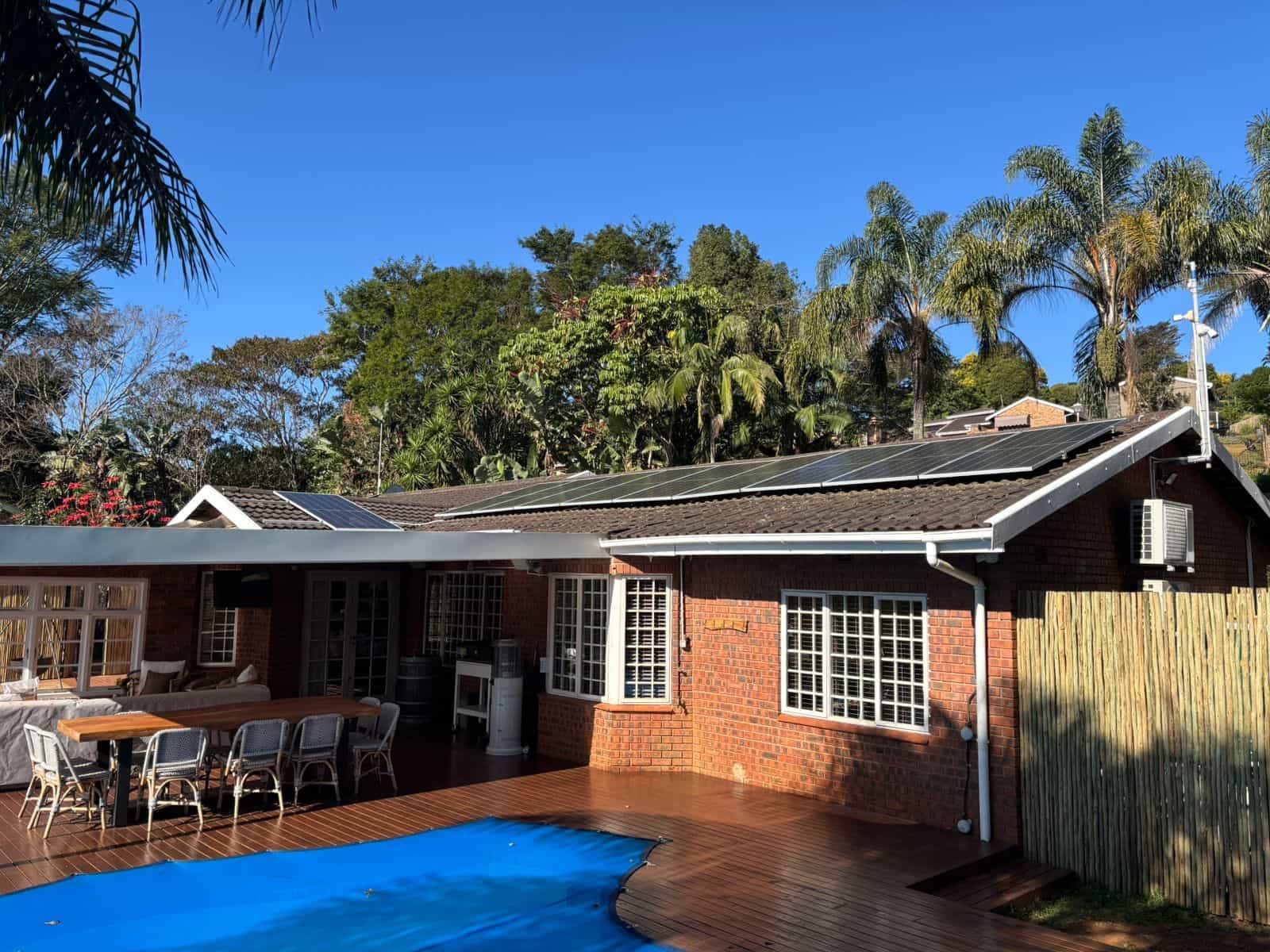 Solar panels on the roof of a red-brick Durban home with a covered patio and swimming pool.