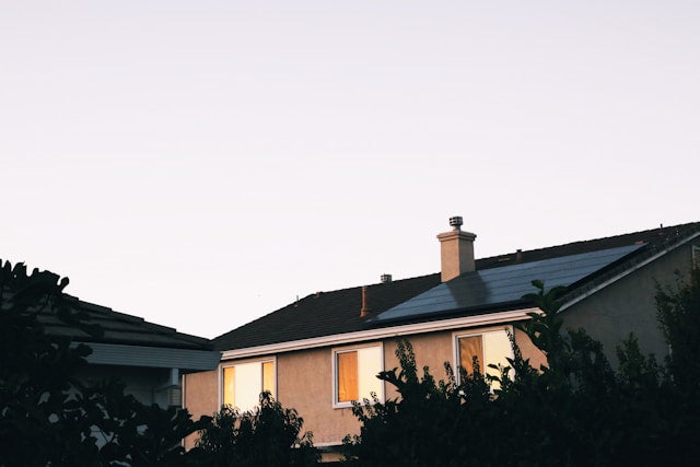 Residential home with solar panels installed on the roof surrounded by green plants.